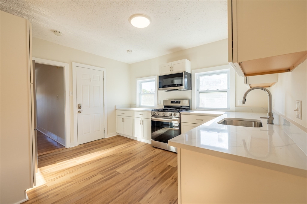 365 Whiting Avenue, Unit 2 Dedham, MA 02026 - Photo 4 of 15 a kitchen with a stove a sink and a microwave