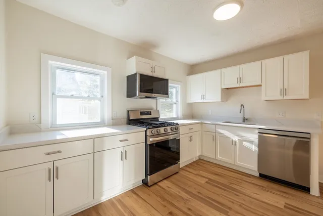 a kitchen with cabinets stainless steel appliances a sink and a window
