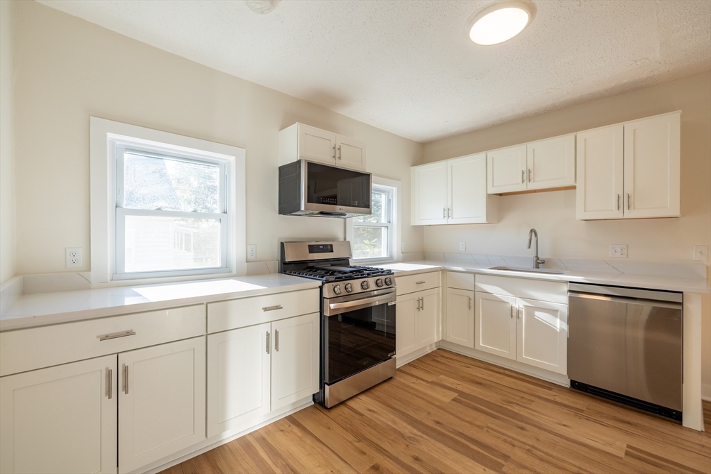 365 Whiting Avenue, Unit 2 Dedham, MA 02026 - Photo 5 of 15 a kitchen with cabinets stainless steel appliances a sink and a window