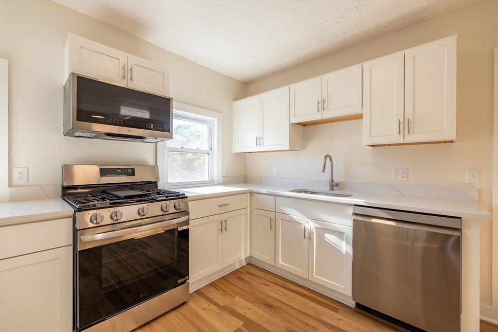 365 Whiting Avenue, Unit 2 Dedham, MA 02026 - Photo 6 of 15 a kitchen with cabinets stainless steel appliances a sink and a microwave