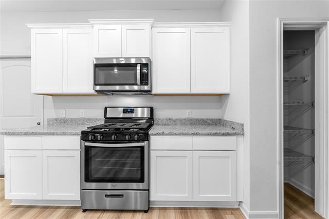 1226 Parker Drive Princeton, TX 75407 - Photo 12 of 35 Kitchen featuring stainless steel appliances, white cabinets, light wood finished floors, and light stone countertops