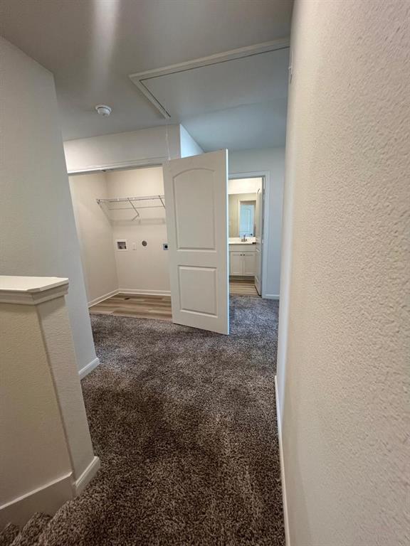 1226 Parker Drive Princeton, TX 75407 - Photo 14 of 35 Corridor with dark colored carpet, a textured wall, and attic access