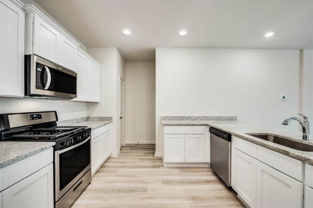 1226 Parker Drive Princeton, TX 75407 - Photo 2 of 35 Kitchen with appliances with stainless steel finishes, white cabinetry, light wood finished floors, recessed lighting, and light stone counters