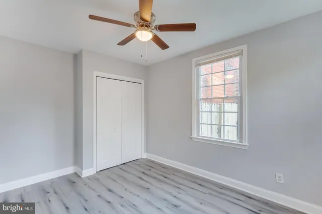 an empty room with wooden floor ceiling fan and windows