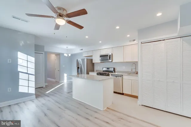 a kitchen with stainless steel appliances kitchen island hardwood floor sink and stove