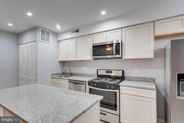 a kitchen with stainless steel appliances granite countertop a sink stove microwave and refrigerator