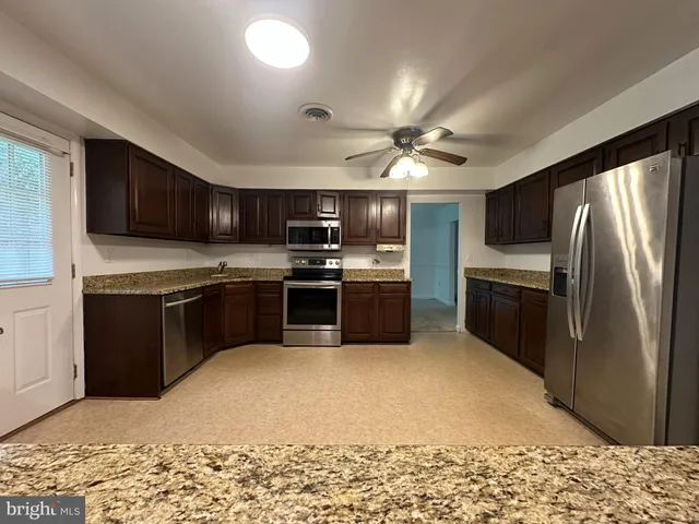 a kitchen with stainless steel appliances granite countertop a stove a sink dishwasher a refrigerator and a microwave oven