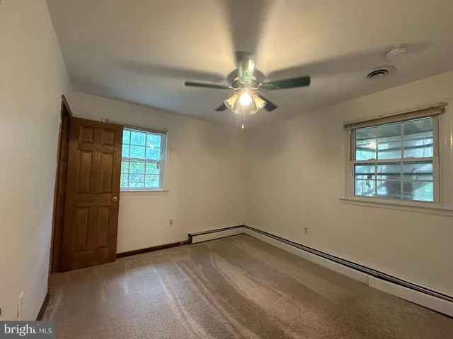 en empty room with windows and ceiling fan