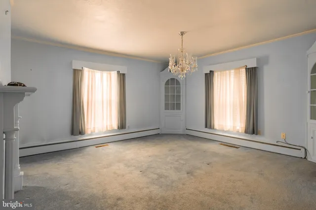 an empty room that has a chandelier and a chandelier fan