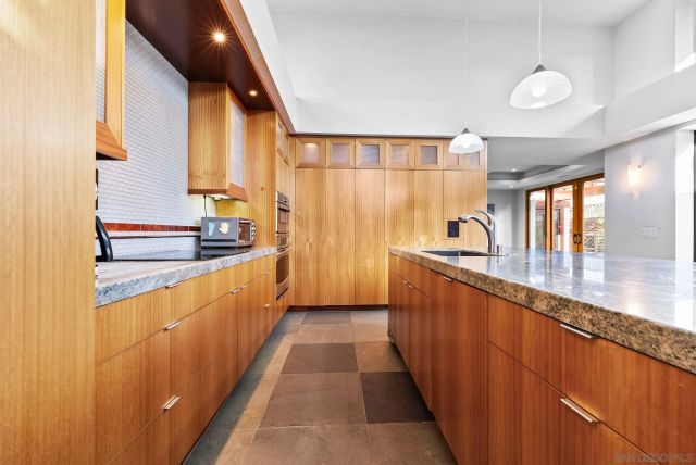 a large kitchen with stainless steel appliances a large counter top a sink a window and living room view