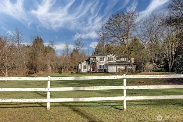 a view of a house with a big yard and large trees