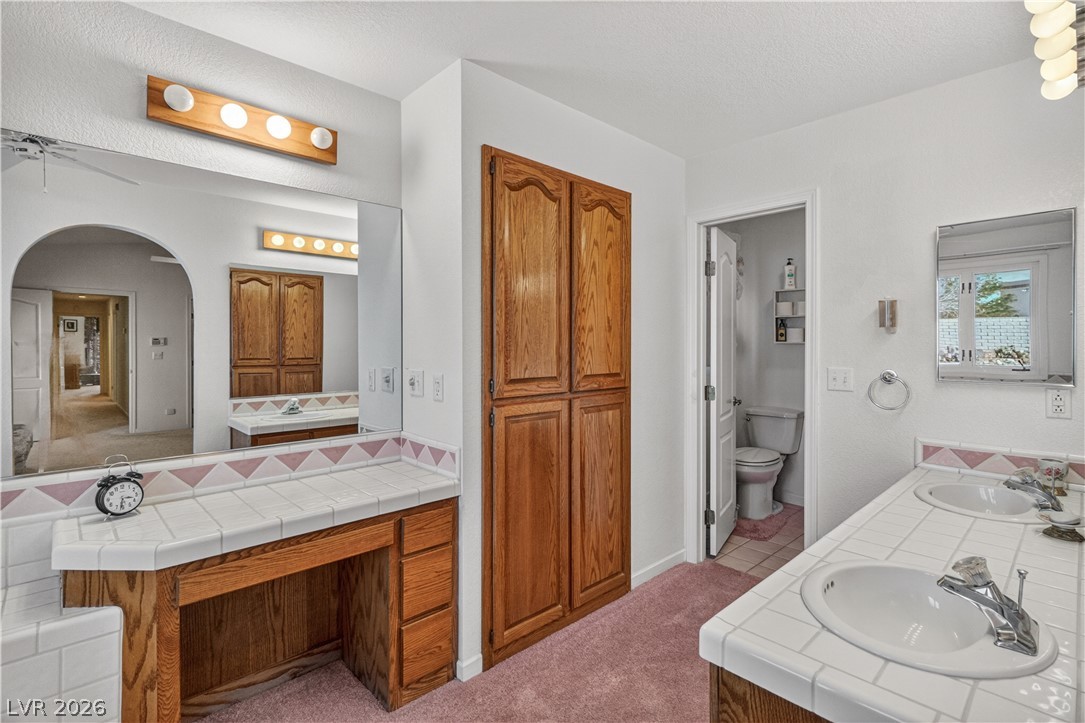 2055 Cholla Way Laughlin, NV 89029 - Photo 35 of 87 Double vanity with a tiled counter, a built-in dressing table, and ample storage.