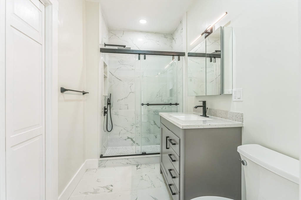 47 Brackett Street, Unit 3 Boston, MA 02135 - Photo 18 of 34 a bathroom with a granite countertop sink a mirror and a shower
