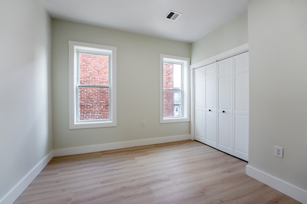 47 Brackett Street, Unit 3 Boston, MA 02135 - Photo 24 of 34 an empty room with wooden floor and windows