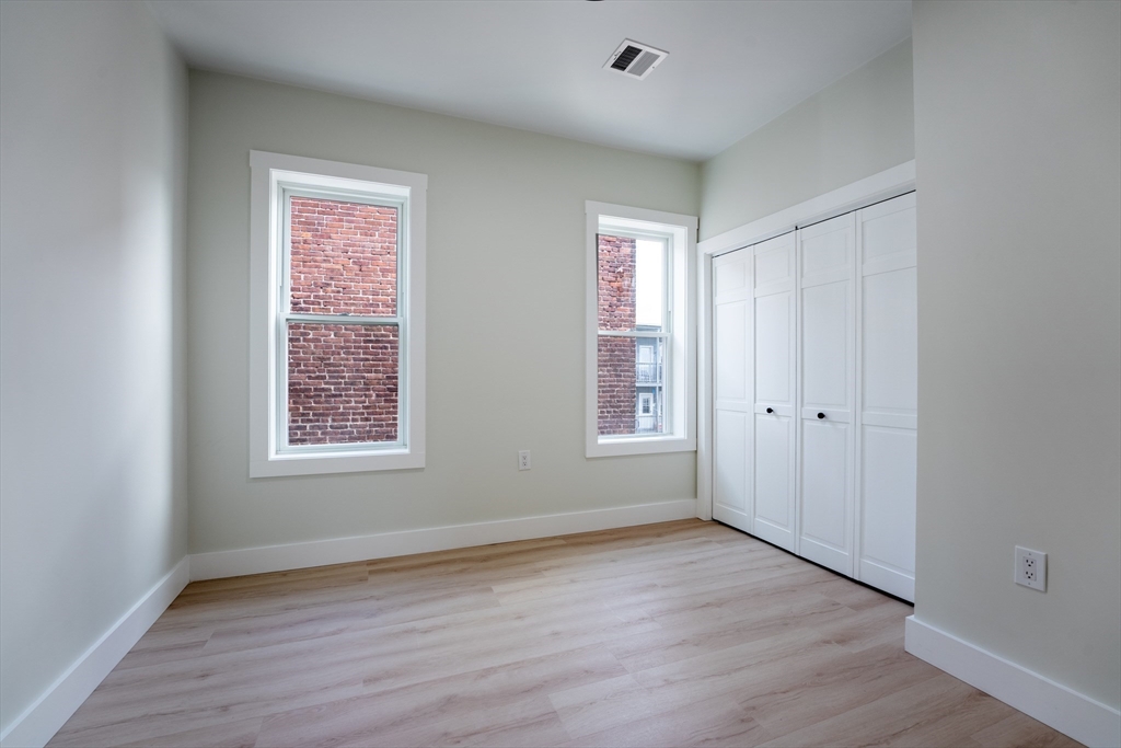 47 Brackett Street, Unit 3 Boston, MA 02135 - Photo 28 of 34 an empty room with wooden floor and windows