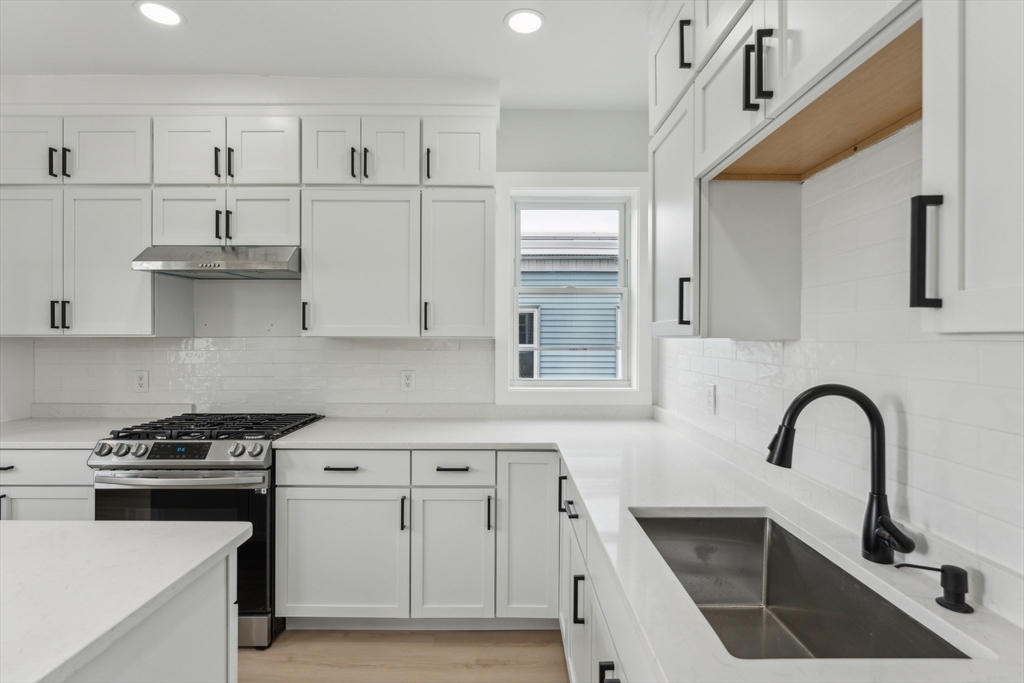47 Brackett Street, Unit 3 Boston, MA 02135 - Photo 4 of 34 a kitchen with granite countertop a stove a sink and white cabinets with wooden floor