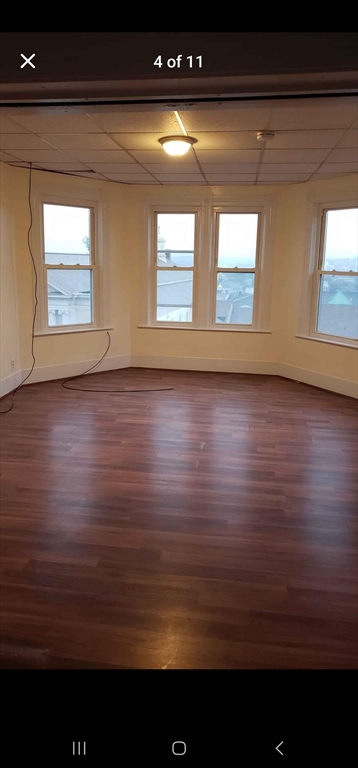 37 Vernon Street Worcester, MA 01610 - Photo 3 of 8 a view of an empty room with wooden floor and a window