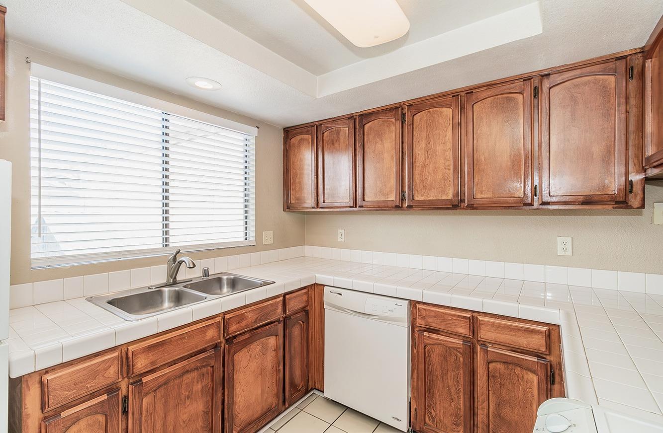 7675 North First Street, Unit 202 Fresno, CA 93720 - Photo 18 of 19 a kitchen with stainless steel appliances granite countertop wooden cabinets a sink and a window