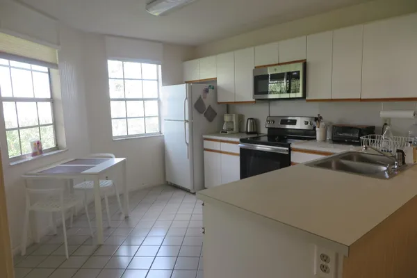 a kitchen with stainless steel appliances granite countertop a sink a stove a microwave a refrigerator a window and white cabinets