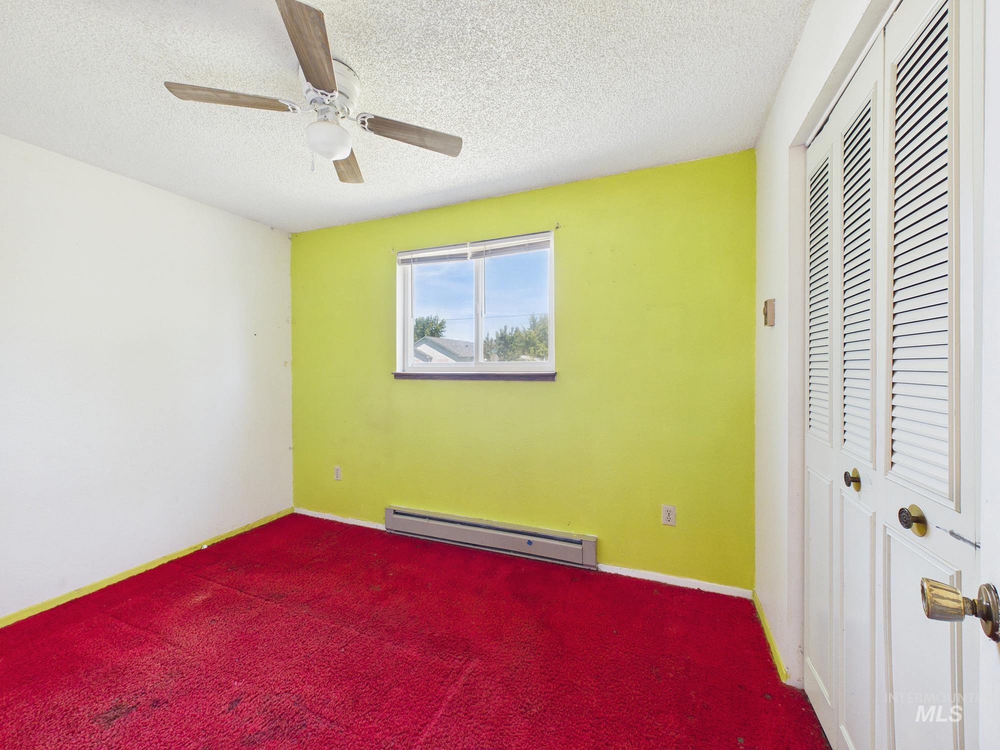 1527 North Plaza Road Emmett, ID 83617 - Photo 23 of 33 Room featuring a window, ceiling fan, baseboard heater, and bi-fold louvered closet doors