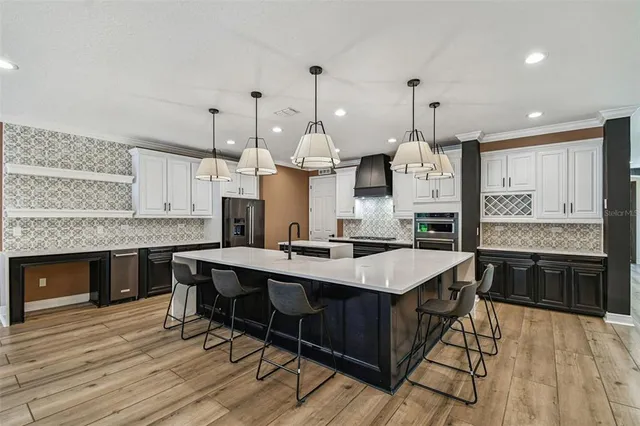 a kitchen with stainless steel appliances granite countertop a sink a stove and a wooden floors