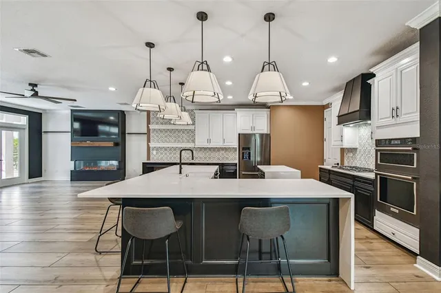a view of a living room kitchen with stainless steel appliances wooden floor and windows