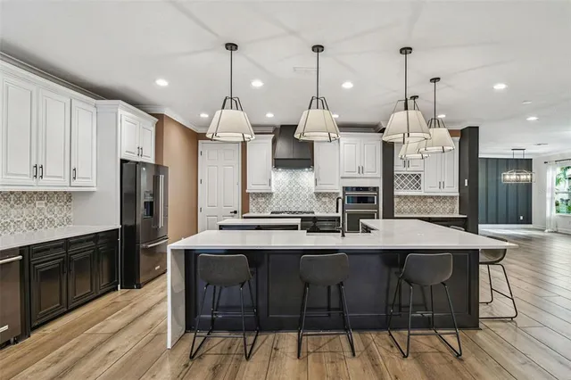 a kitchen with stainless steel appliances kitchen island granite countertop a sink a stove and a refrigerator