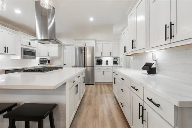 a large white kitchen with stainless steel appliances sink and cabinets