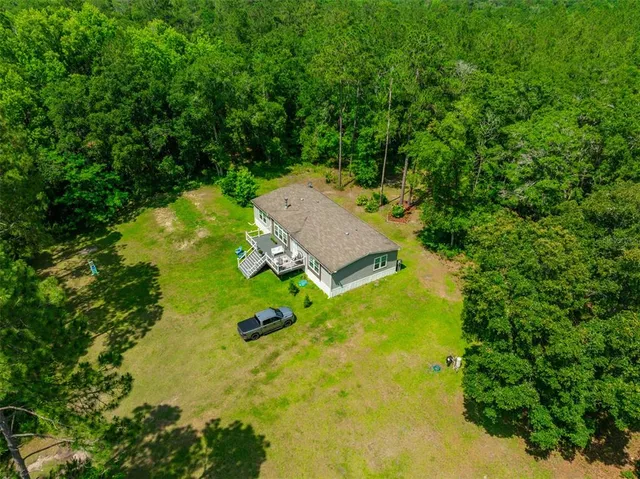 an aerial view of a house with swimming pool a yard and trees