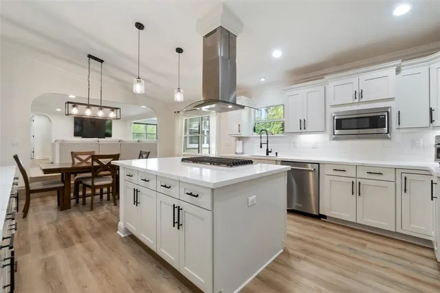 a kitchen with stainless steel appliances granite countertop a sink a stove and a wooden floors