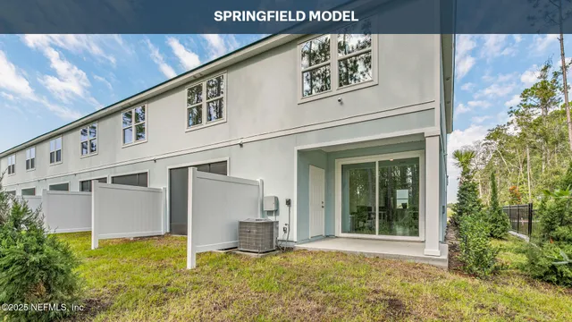 a view of a white house with large windows and plants