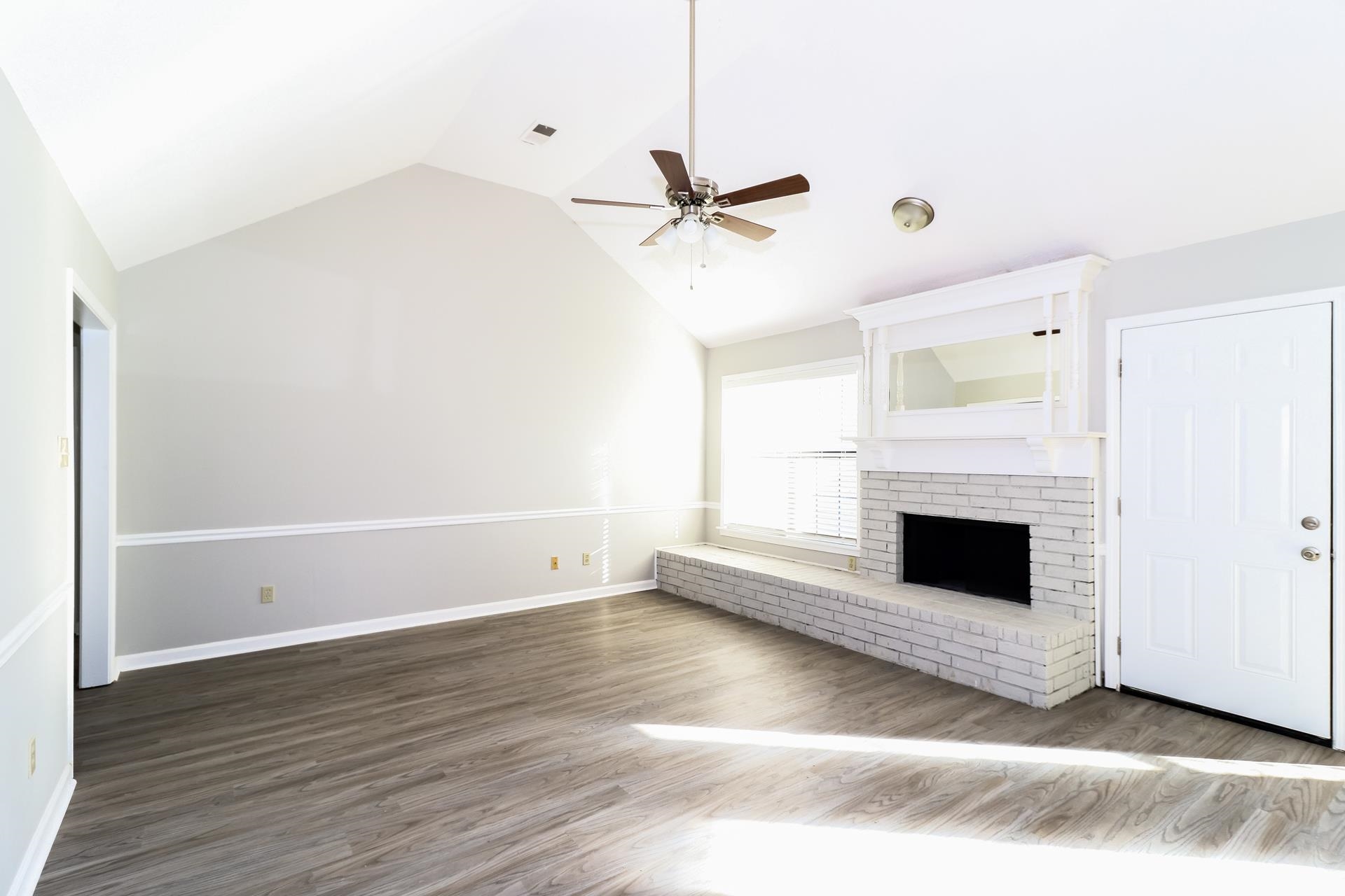 5921 Pecan Trace Memphis, TN 38135 - Photo 2 of 16 Unfurnished living room featuring vaulted ceiling, wood finished floors, a fireplace, and ceiling fan