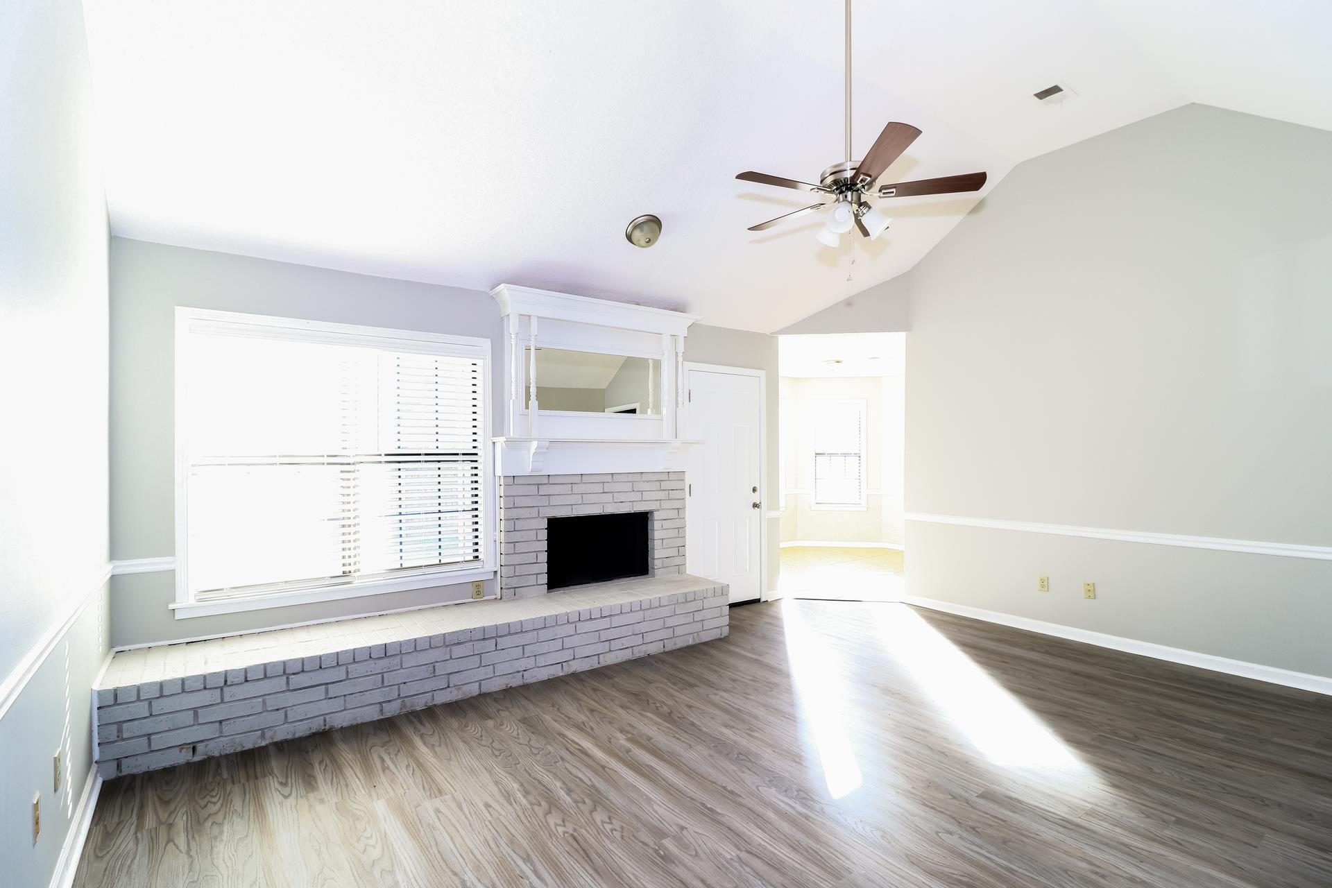 5921 Pecan Trace Memphis, TN 38135 - Photo 3 of 16 Unfurnished living room with wood finished floors, a brick fireplace, ceiling fan, and high vaulted ceiling