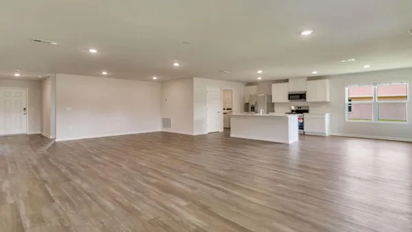 a view of a big room with wooden floor and windows