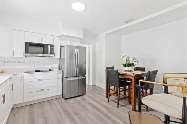 a kitchen with stainless steel appliances a stove top oven a refrigerator cabinets and dining table