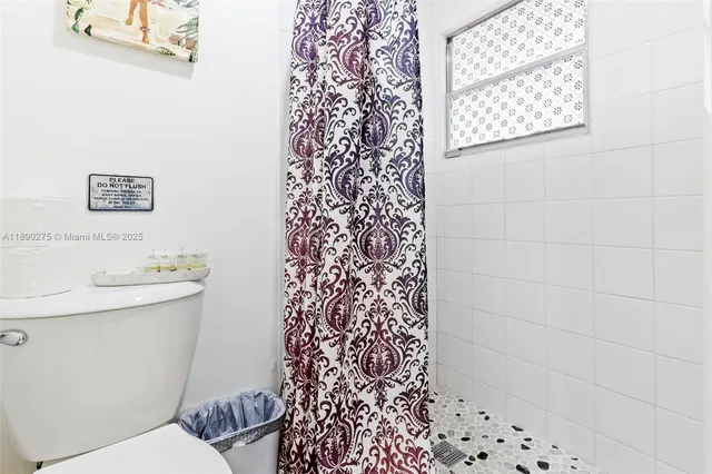 a bathroom with a toilet and a shower curtain
