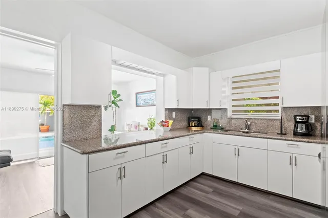 a kitchen with a sink dishwasher window and cabinets