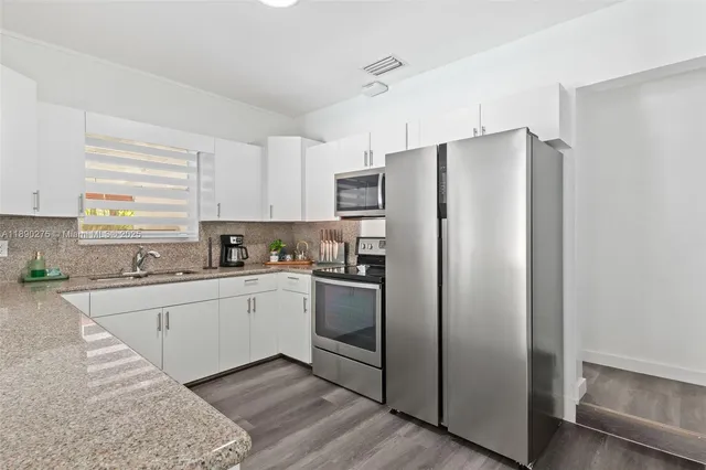 a kitchen with stainless steel appliances granite countertop a refrigerator and a stove top oven