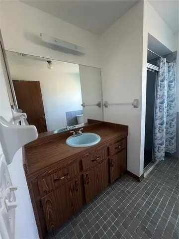 a bathroom with a granite countertop sink a mirror and shower