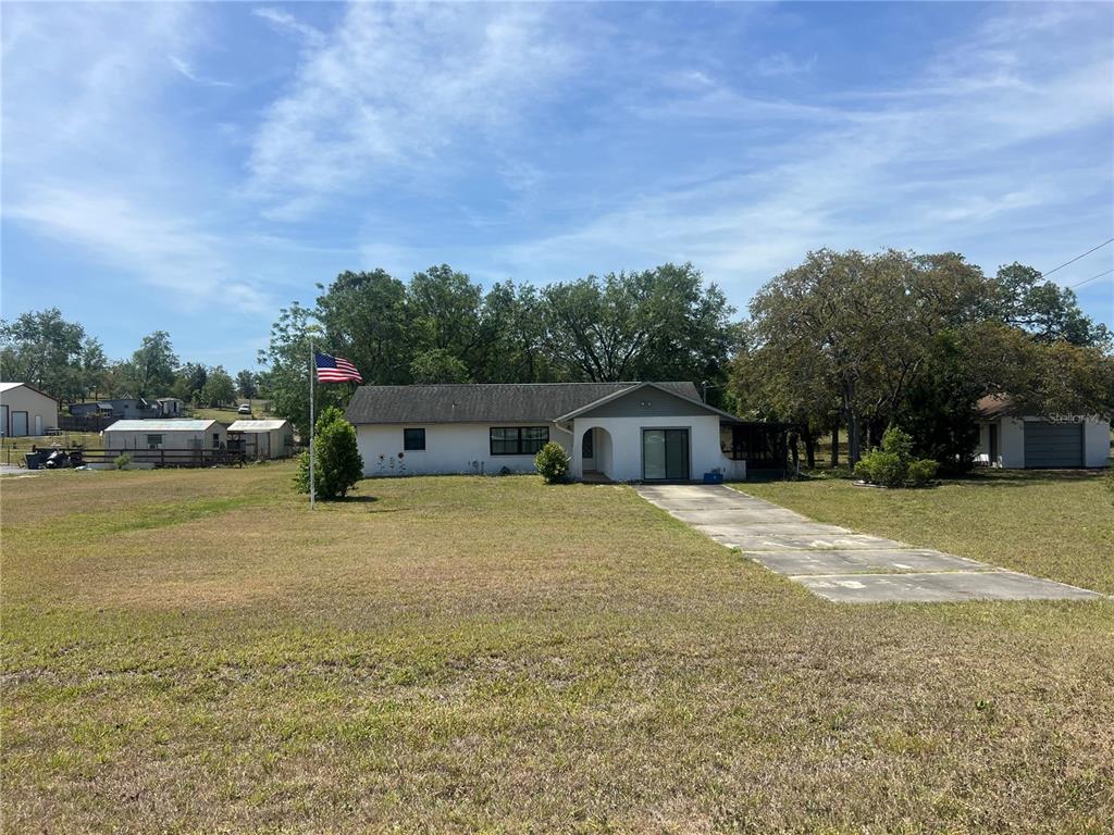 13020 Sun Road Brooksville, FL 34613 - Photo 3 of 33 a front view of a house with a garden and trees