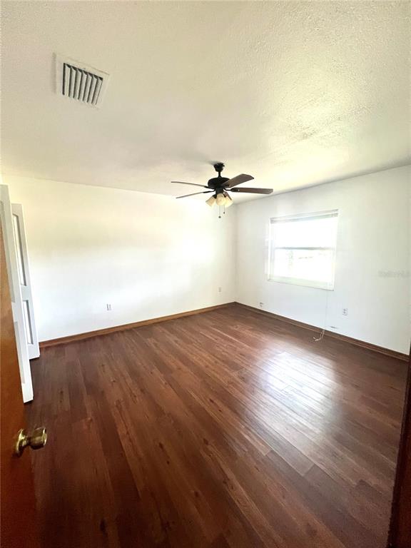 13020 Sun Road Brooksville, FL 34613 - Photo 7 of 33 an empty room with wooden floor fan and windows