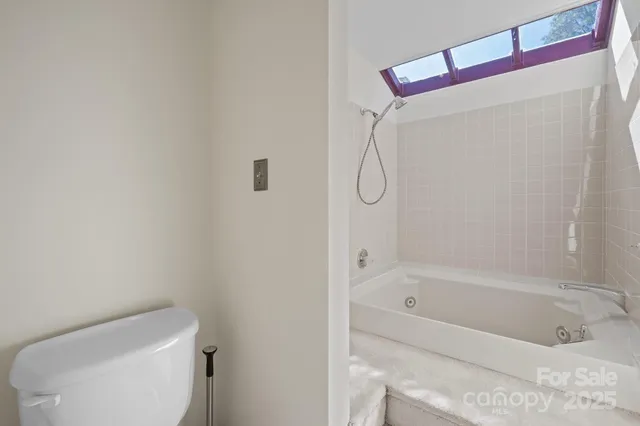 a white bath tub sitting next to a white toilet and a shower