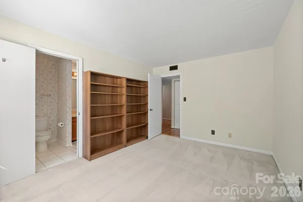 a view of an empty room with a closet and wooden shelves