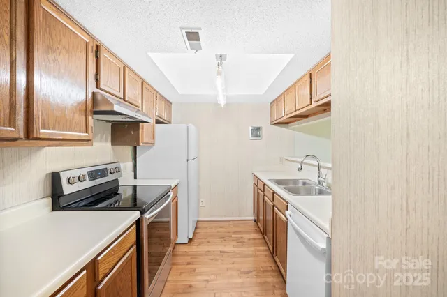 a kitchen with stainless steel appliances granite countertop a refrigerator a stove and a sink with wooden floor