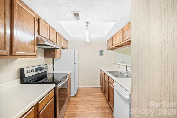 a kitchen with stainless steel appliances granite countertop a refrigerator a stove and a sink with wooden floor