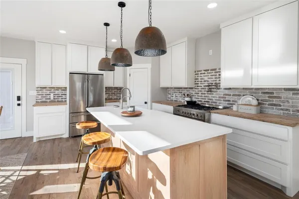 a kitchen with stainless steel appliances kitchen island granite countertop a sink a stove and a wooden floors