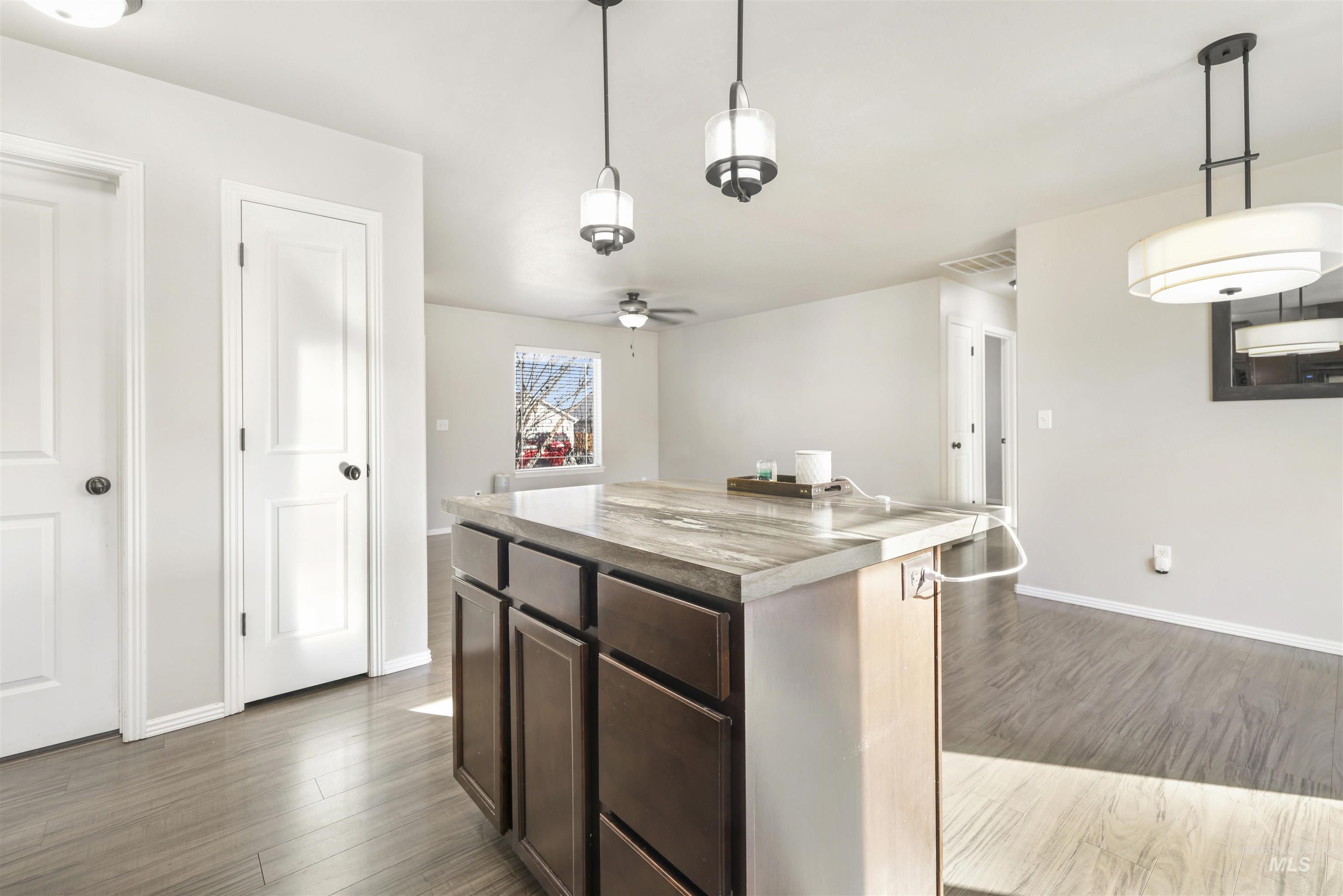 370 Feather Avenue Twin Falls, ID 83301 - Photo 5 of 17 Kitchen with dark brown cabinetry, a kitchen island, hanging light fixtures, and dark wood finished floors