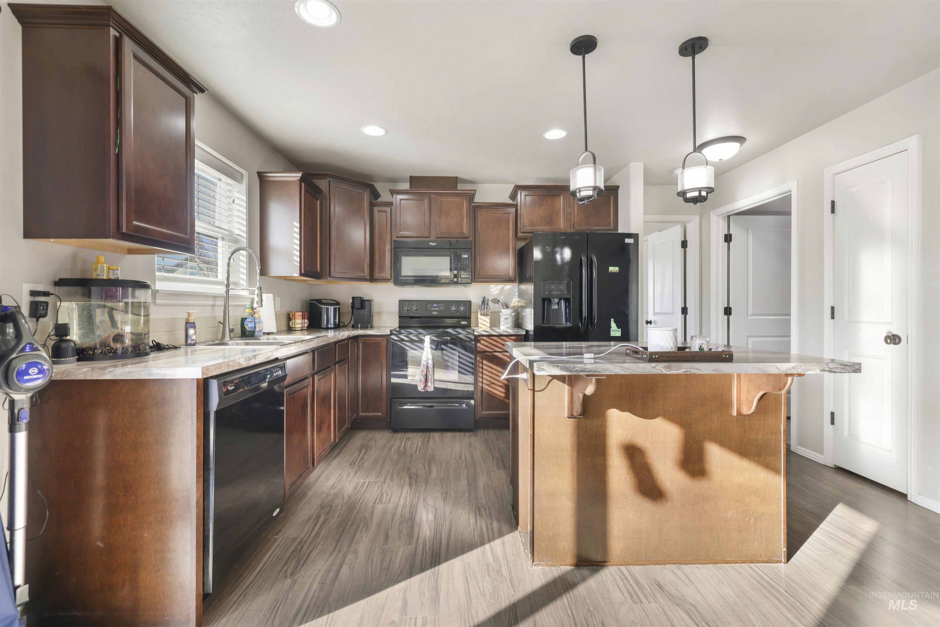 370 Feather Avenue Twin Falls, ID 83301 - Photo 7 of 17 Kitchen featuring black appliances, dark brown cabinets, decorative light fixtures, recessed lighting, and a center island