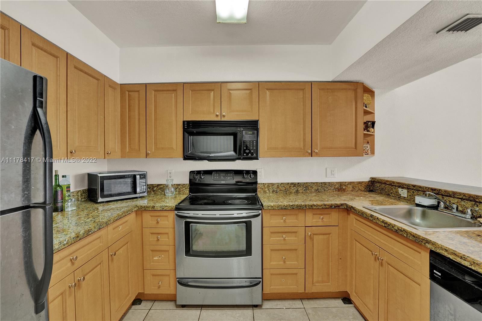 a kitchen with granite countertop a sink stove and microwave