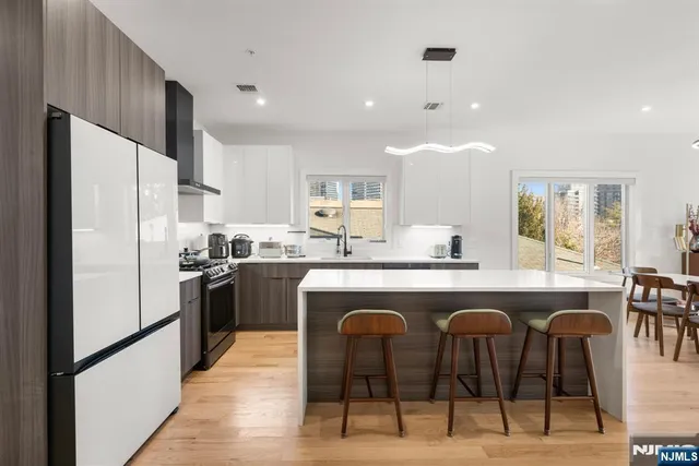 a kitchen with stainless steel appliances granite countertop a refrigerator a sink a stove a dining table and chairs